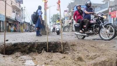 Commuters on the pothole-riddled Basai Road in Gurugram. (PTI) Commuters on the pothole-riddled Basai Road in Gurugram. (PTI)