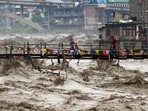 Residents run across a bridge over the flooding Beas River following incessant rains in Kullu, Himachal Pradesh.(AP)