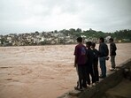 People look on as the river Tawi flows above the danger level following flash floods triggered by heavy rainfall, at Gorkha Nagar in Jammu on Tuesday.