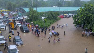 Commuters making their way through a waterlogged road in Gurugram. (PTI)