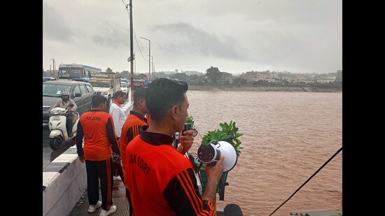 An SDRF personnel announces to vacate the surrounding area as the water levels of the Tawi River rise, in Jammu on Tuesday. (ANI)