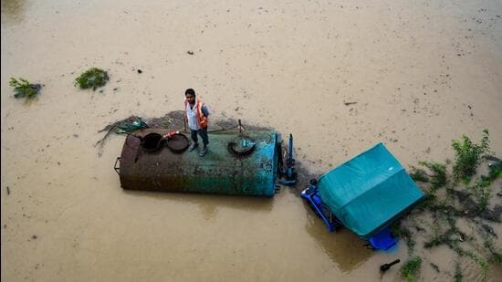 A man with his vehicle was stuck in the floodwaters at Yamuna Khadar, near Mayur Vihar, on Wednesday. (RAJ K RAJ /HT PHOTO)