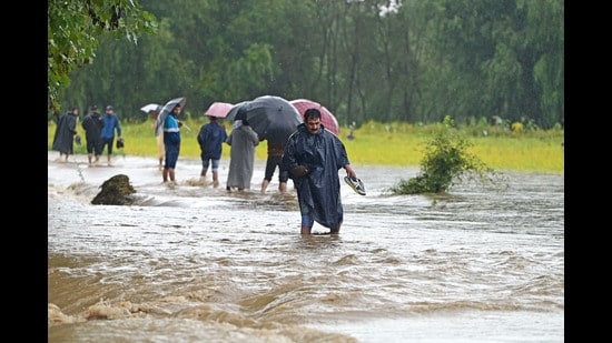People wade through a flooded road in Tailbal area of Srinagar, on Wednesday. (Waseem Andrabi /HT)