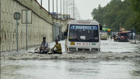 Vehicles wade through the waterlogged street in Vinod Nagar area near NH-24 on Wednesday. (RAJ K RAJ /HT PHOTO)