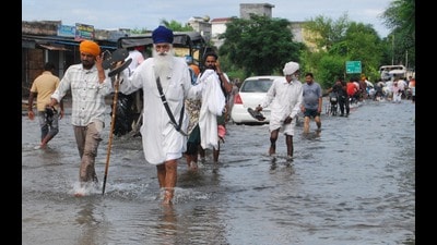 Residents wading through floodwaters at a village near Ajnala in Amritsar on Thursday. (Sameer Sehgal/HT)