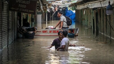 Some people use a boat as others walk through a flooded Monastery Market as the Yamuna river continues to flow in spate in Delhi (PTI)