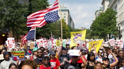 Demonstrators hold inverted US flags during the "We Are All DC" national march in solidarity with DC communities and calling for an end to the deployment of National Guard troops in Washington, DC, on September 6, 2025. (Photo by Amid FARAHI / AFP) (AFP)