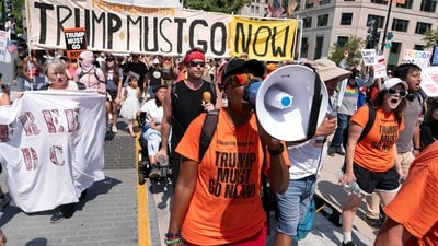 Demonstrators with a ‘Trump must go now’ banner marched to protest the deployment of the National Guard in Washington, DC. (AP)