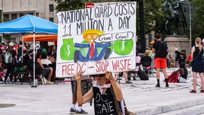 A demonstrator holds a sign calling out Trump for wasting millions on the deployment of National Guard in Washington (Bloomberg)