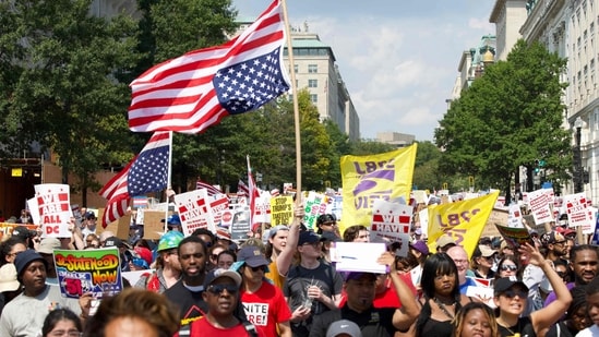 Demonstrators hold inverted US flags during the "We Are All DC" national march in solidarity with DC communities and calling for an end to the deployment of National Guard troops in Washington, DC, on September 6, 2025. (Photo by Amid FARAHI / AFP)(AFP)