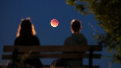 Onlookers watch the total lunar eclipse, also known as the blood moon, from a park bench, in Leipzig, Germany. (AP)