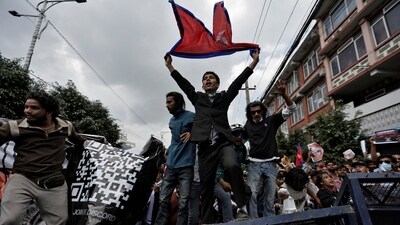 Demonstrators with the Nepal flag shout slogans as they stand on a barricade during the protest on Monday (Reuters)