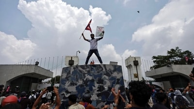 A demonstrator waves a flag as he stands atop a vehicle near the entrance of the Nepal Parliament during a protest against corruption and the government’s decision to block several social media platforms, in Kathmandu on September 8, 2025. (Navesh Chitrakar/Reuters)