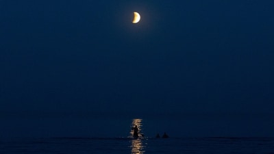 Beach-goers rest on a shore of the Black Sea with a full moon also known as "Blood Moon" during a phase of a total eclipse in the background in Odesa, on September 7, 2025, amid the Russian invasion of Ukraine. (AFP)