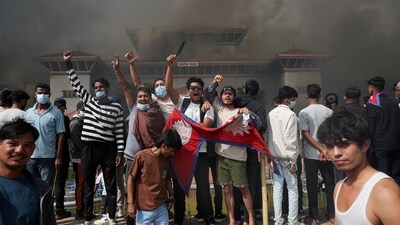 A demonstrator holds a knife and Nepal's flag as smoke rises at the Parliament complex during a protest against Monday's killing of 19 people after anti-corruption protests that were triggered by a social media ban, which was later lifted, during a curfew in Kathmandu, Nepal, September 9, 2025. REUTERS/Adnan Abidi (REUTERS)