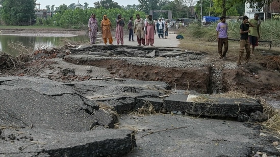 Villagers stand near a damaged road after a rise in the water level of the Ravi River following heavy monsoon rains in the Ghonewala village near Punjab's Amritsar (AFP)