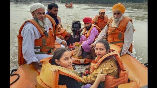 NDRF personnel with evacuated persons during a rescue operation in a flood-affected area of Punjab. (PTI Photo)