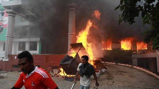 Demonstrators walk past flames outside the burning Nepali Congress Party office during a protest to condemn the police's deadly crackdown on demonstrators in Kathmandu (AFP)