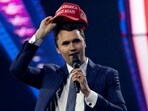 Charlie Kirk, Turning Point USA founder, puts on a MAGA hat during the AmericaFest 2024 conference 
