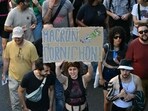 A protester in Marseille holds a placard reading "Macron Cornichon" during nationwide protests that erupted after handover of power between the new Prime Minister and his predecessor, who suffered a crushing loss in a confidence vote.