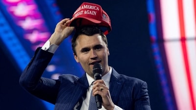 Charlie Kirk, Turning Point USA founder, puts on a MAGA hat during the AmericaFest 2024 conference (REUTERS)