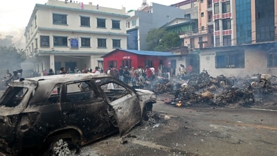 People gather near a charred vehicle, set ablaze by protesters inside the premises of the Nepal Traffic Police head office in Kathmandu. (Prabin Ranabhat/AFP)