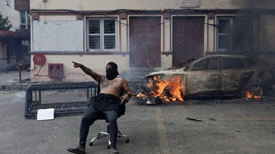 A demonstrator sits on a chair next to a burning car at the Nepal Supreme Court during a protest. (REUTERS)