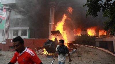 Demonstrators walk past flames outside the burning Nepali Congress Party office during a protest to condemn the police's deadly crackdown on demonstrators in Kathmandu. (Prabin Ranabhat/AFP)