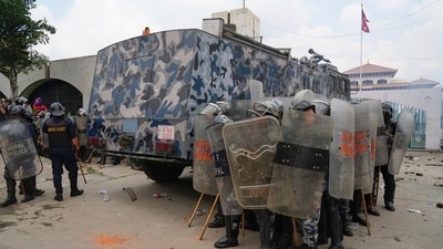 Riot police take cover behind an armored vehicle during clashes with protesters outside the Parliament building in Kathmandu, Nepal. (Niranjan Shrestha/AP)