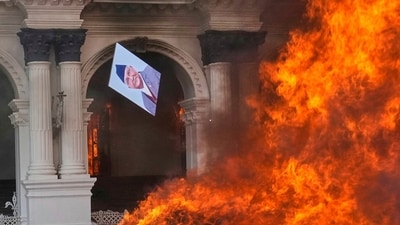A protester throws a photograph of Nepal Prime Minister Khadga Prasad Oli in the fire at the Singha Durbar. (Niranjan Shrestha/AP)