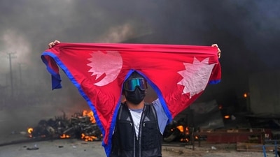A protester shouts slogans carrying national flag after burning down a police station during protests against social media ban and corruption in Kathmandu, Nepal. (Niranjan Shrestha/AP)