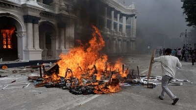 A demonstrator holding a police shield approaches the burning items at the Singha Durbar office complex that houses the Prime Minister's office and other ministries. (Navesh Chitrakar/Reuters)
