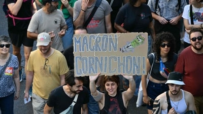 A protester in Marseille holds a placard reading "Macron Cornichon" during nationwide protests that erupted after handover of power between the new Prime Minister and his predecessor, who suffered a crushing loss in a confidence vote. (Cristophe Simon/AFP) A protester in Marseille holds a placard reading "Macron Cornichon" during nationwide protests that erupted after handover of power between the new Prime Minister and his predecessor, who suffered a crushing loss in a confidence vote. (Cristophe Simon/AFP)