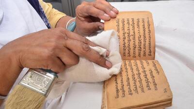A woman cleans a rare old manuscript in gurbani. (HT File Photo) A woman cleans a rare old manuscript in gurbani. (HT File Photo)