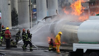 Firefighters spray hoses at a gas tanker that exploded under a highway overpass in Mexico City. (AP)