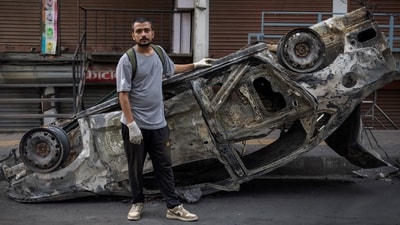Avash Regmi, 25, a freelance photographer who participated in the Gen Z protests in Nepal, stands next to a burnt car as he takes part in a cleaning campaign in Kathmandu. (Reuters)