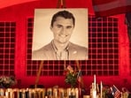 A person holds a US flag as people pay their respects at a makeshift memorial on the Utah Valley University campus in Orem, Utah, in front of a photo of youth activist and influencer Charlie Kirk, a day after he was shot during a public event on September 11, 2025. 