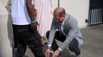 Britain's Prince Harry checks a shoe of Trevor Rose, head of the Community Recording Studio (CRS), a grassroots institution providing opportunities for young people, during a visit to CRS, in Nottingham, Britain, September 9, 2025. REUTERS/Phil Noble      TPX IMAGES OF THE DAY (REUTERS)