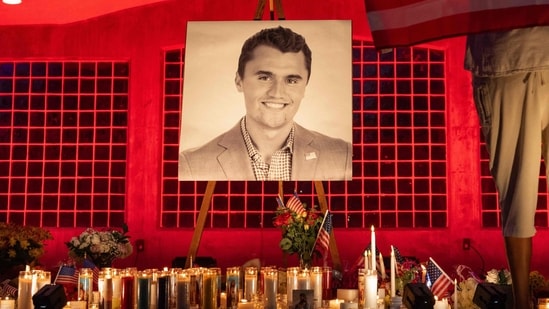 A person holds a US flag as people pay their respects at a makeshift memorial on the Utah Valley University campus in Orem, Utah, in front of a photo of youth activist and influencer Charlie Kirk, a day after he was shot during a public event on September 11, 2025. (AFP)