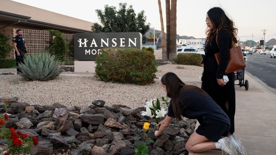 A woman places flowers at a makeshift memorial outside the mortuary where the body of slain conservative activist Charlie Kirk was delivered(Reuters)