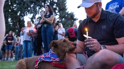 A man sits with a dog during a candlelight vigil for right-wing activist Charlie Kirk at a makeshift memorial at Memorial Park in Provo, Utah, on September 12, 2025, after he was shot during a public event at Utah Valley University. (AFP) A man sits with a dog during a candlelight vigil for right-wing activist Charlie Kirk at a makeshift memorial at Memorial Park in Provo, Utah, on September 12, 2025, after he was shot during a public event at Utah Valley University. (AFP)