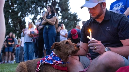 A man sits with a dog during a candlelight vigil for right-wing activist Charlie Kirk at a makeshift memorial at Memorial Park in Provo, Utah, on September 12, 2025, after he was shot during a public event at Utah Valley University.&nbsp;(AFP)