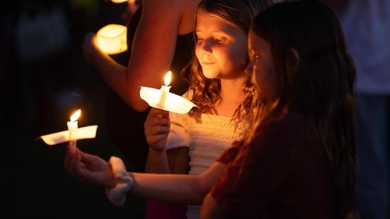 A young girl holds a candle during a candlelight vigil for right-wing activist Charlie Kirk at a makeshift memorial at Memorial Park in Provo, Utah, on September 12, 2025, after he was shot during a public event at Utah Valley University. (Photo by Melissa MAJCHRZAK / AFP)(AFP)