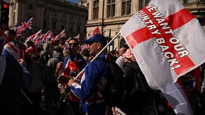 A man holds a flag that reads "We want our country back," as protesters gather on the day of an anti-immigration rally organised by British anti-immigration activist Stephen Yaxley-Lennon (Reuters)