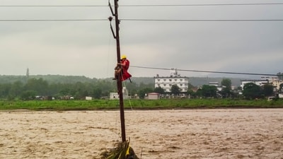 In the video posted by the NDRF, a personnel is seen ziplining to the middle of the flooded river. (PTI) In the video posted by the NDRF, a personnel is seen ziplining to the middle of the flooded river. (PTI)