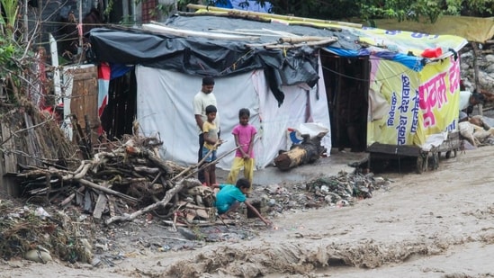 Dehradun cloudburst: People stand near a temporary shelter at a flooded area as the Chandrabhaga river flows in spate due to heavy rains, in Rishikesh on Tuesday. Dehradun cloudburst: People stand near a temporary shelter at a flooded area as the Chandrabhaga river flows in spate due to heavy rains, in Rishikesh on Tuesday.
