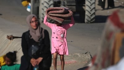 A displaced Palestinian girl carries a mattress as she and her family move with their belongings southwards on a road in the Nuseirat refugee camp area in the central Gaza Strip following renewed Israeli evacuation orders for Gaza City on September 16, 2025. Israel launched its long-anticipated ground assault on Gaza City at dawn on September 16, a day after winning backing from its top ally the United States despite mounting international alarm. (Eyad Baba/AFP) A displaced Palestinian girl carries a mattress as she and her family move with their belongings southwards on a road in the Nuseirat refugee camp area in the central Gaza Strip following renewed Israeli evacuation orders for Gaza City on September 16, 2025. Israel launched its long-anticipated ground assault on Gaza City at dawn on September 16, a day after winning backing from its top ally the United States despite mounting international alarm. (Eyad Baba/AFP)