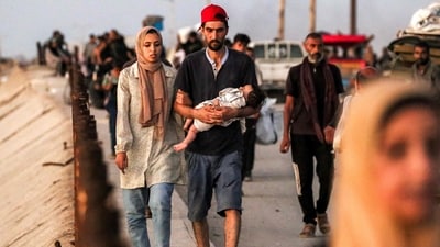 A couple with an infant child walk with other displaced Palestinians evacuating southbound from Gaza City along the coastal road in Nuseirat in the central Gaza Strip. (Eyad Baba/AFP) A couple with an infant child walk with other displaced Palestinians evacuating southbound from Gaza City along the coastal road in Nuseirat in the central Gaza Strip. (Eyad Baba/AFP)