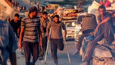 An amputee walks with crutches alongside other displaced Palestinians evacuating southbound from Gaza City, traveling on foot and by vehicle, along the coastal road in Nuseirat in the central Gaza Strip. (Eyad Baba/AFP) An amputee walks with crutches alongside other displaced Palestinians evacuating southbound from Gaza City, traveling on foot and by vehicle, along the coastal road in Nuseirat in the central Gaza Strip. (Eyad Baba/AFP)