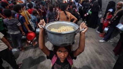 A Palestinian child walks away with a pot of rice obtained from a charity kitchen in the Nuseirat refugee camp in the central Gaza Strip, amid a UN-declared famine after nearly two years of war. (Eyad Baba/AFP) A Palestinian child walks away with a pot of rice obtained from a charity kitchen in the Nuseirat refugee camp in the central Gaza Strip, amid a UN-declared famine after nearly two years of war. (Eyad Baba/AFP)